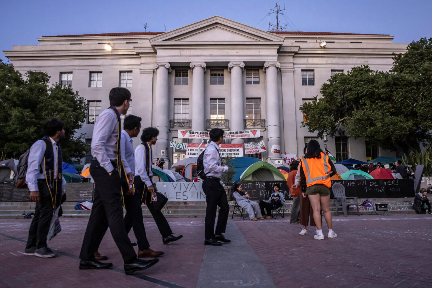 FILE - Students in graduation garb walk by a pro-Palestinian tent encampment on the steps of Sproul...