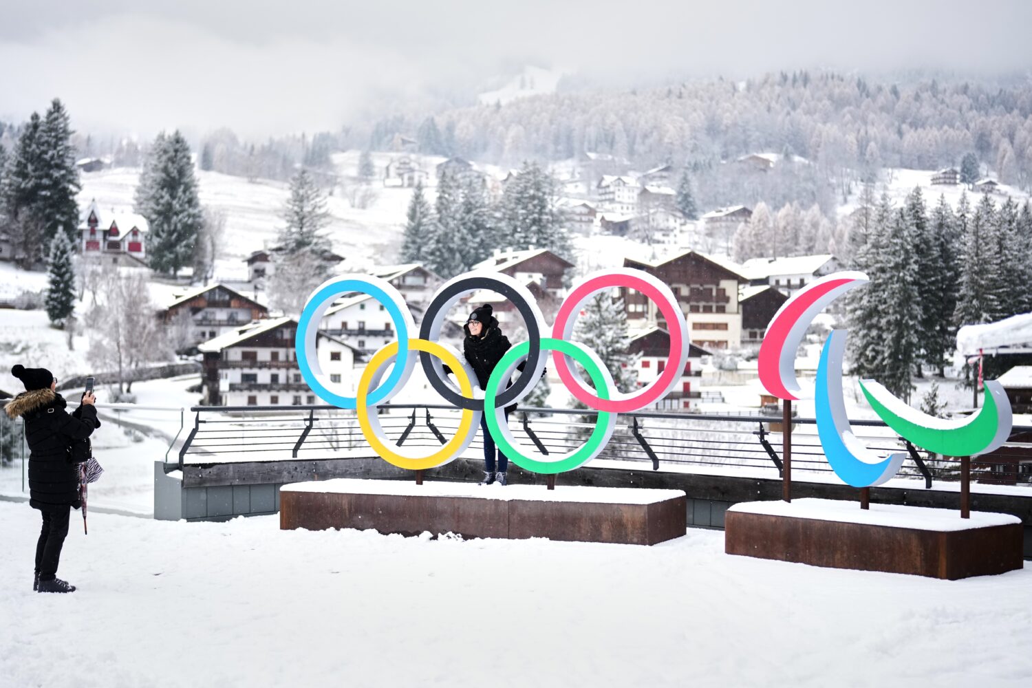FILE - People take photos in front of the Milan Cortina Winter Olympics and Paralympics rings, in C...