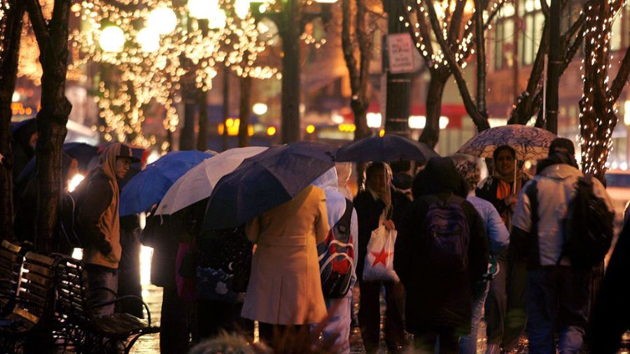 Commuters carry umbrellas as they wait for buses in Rainier Square on 4th Avenue during evening rus...