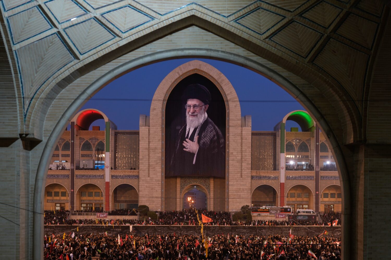 Mourners gather beneath a portrait of the late Iranian Supreme Leader Ayatollah Ali Khamenei during...