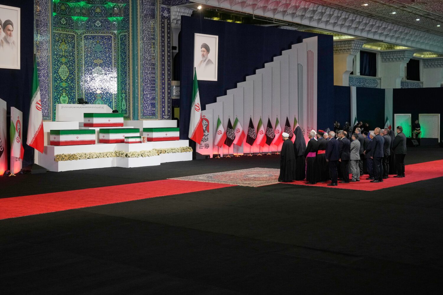 Iranian religious leaders and other mourners pay their respects before the coffins of slain Iranian...