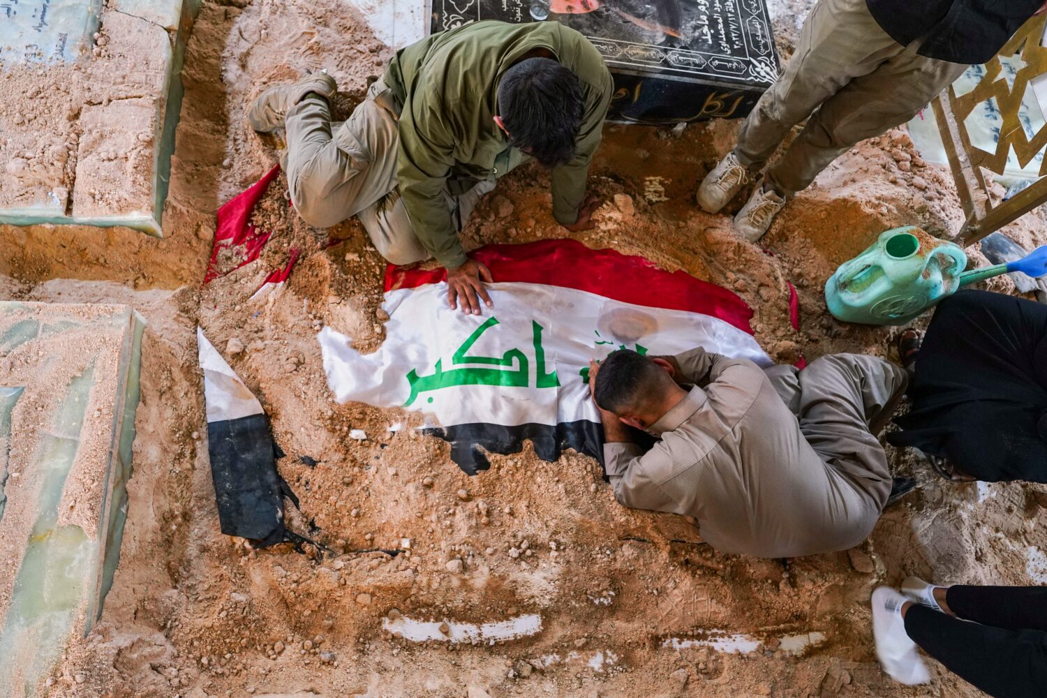 Mourners grieve at the grave of a Popular Mobilization Forces fighter during a funeral for fighters...