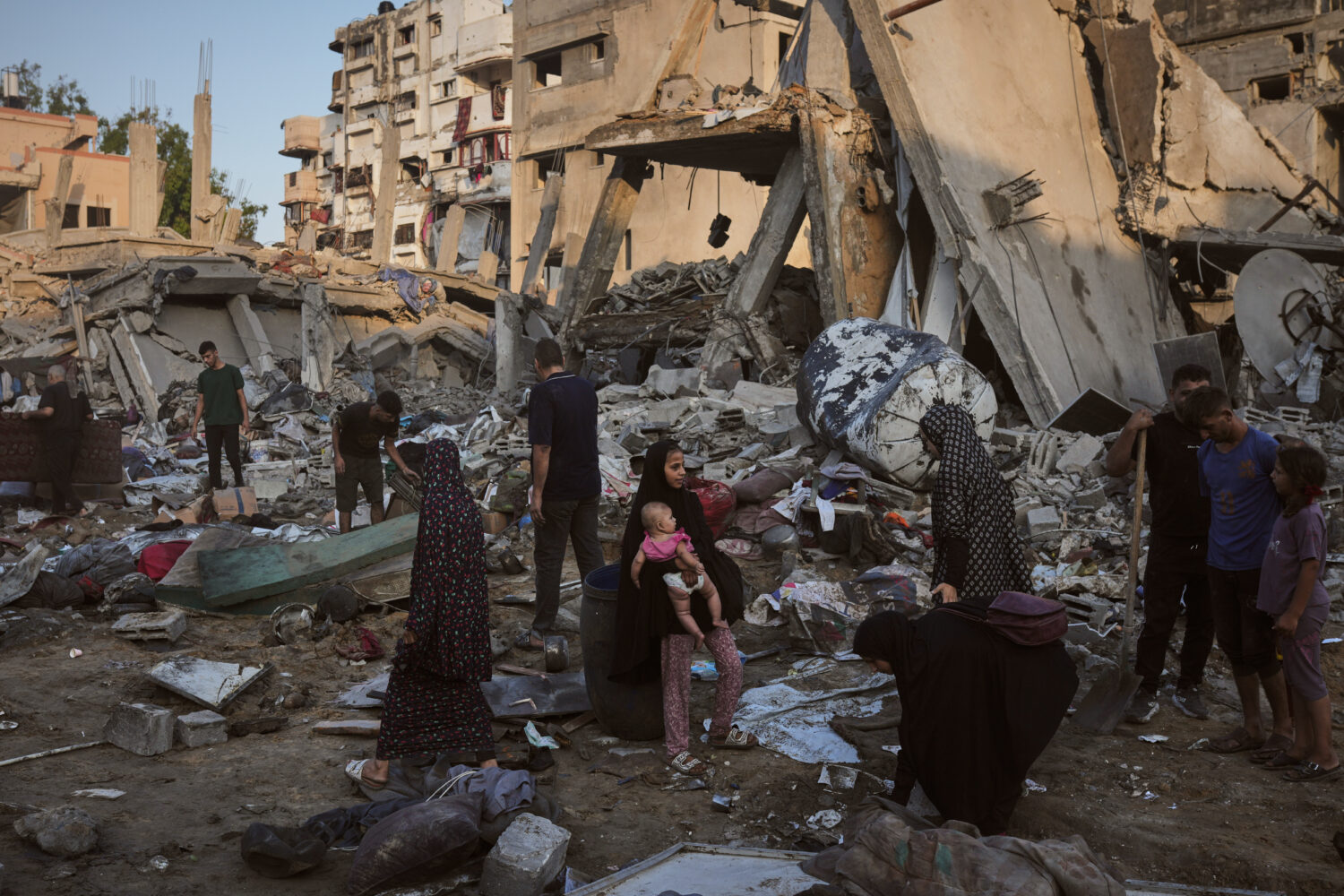 Palestinians salvage their belongings from the rubble of a building and tents destroyed in an Israe...