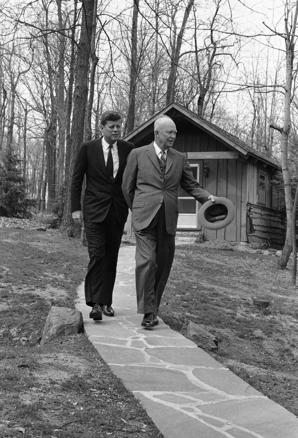 FILE - President John Kennedy and former President Dwight Eisenhower walks along a flagstone path, ...