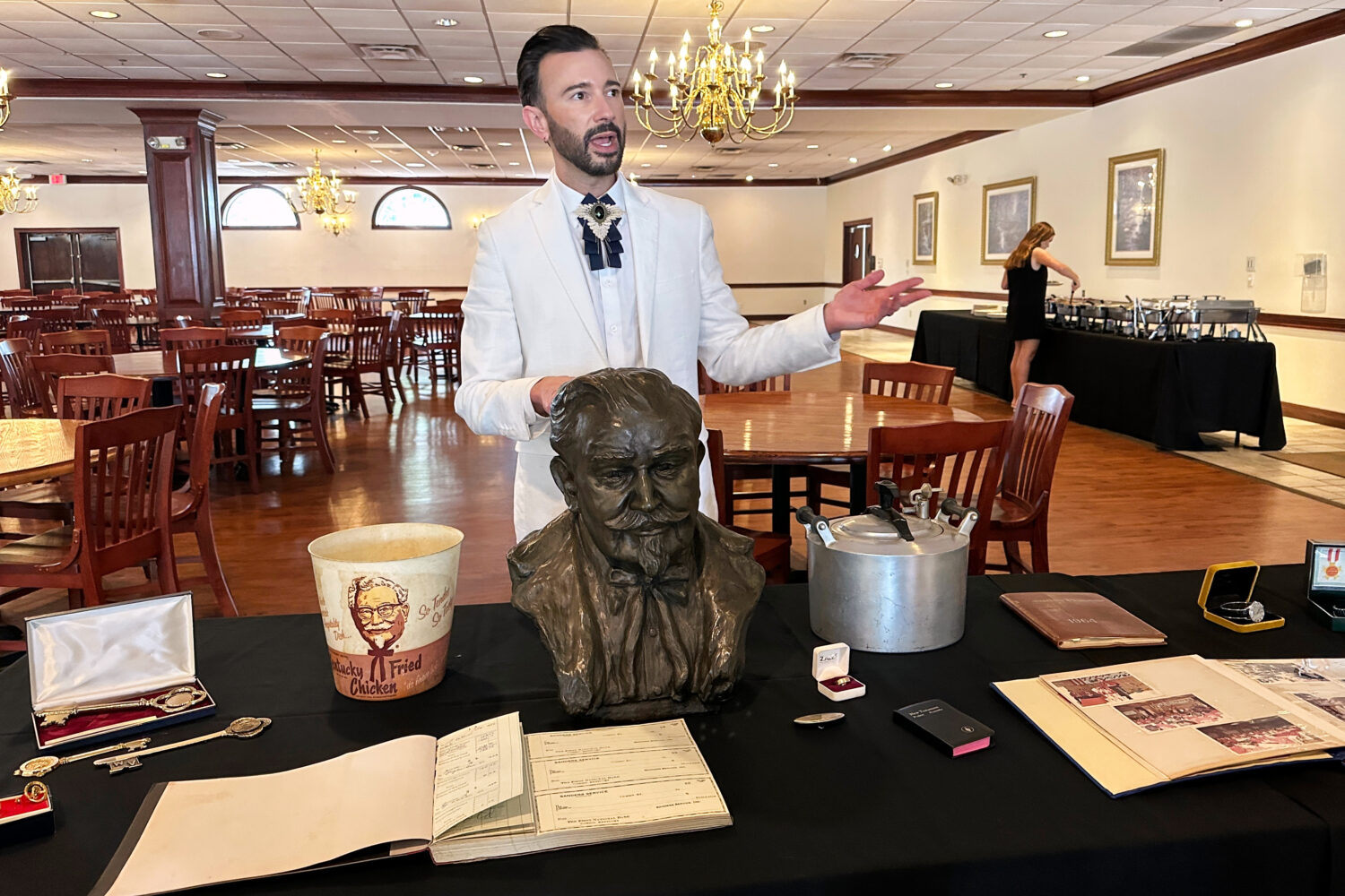 Auctioneer Jonathan Klunk gestures to a display of personal items owned by KFC founder Harland Sand...