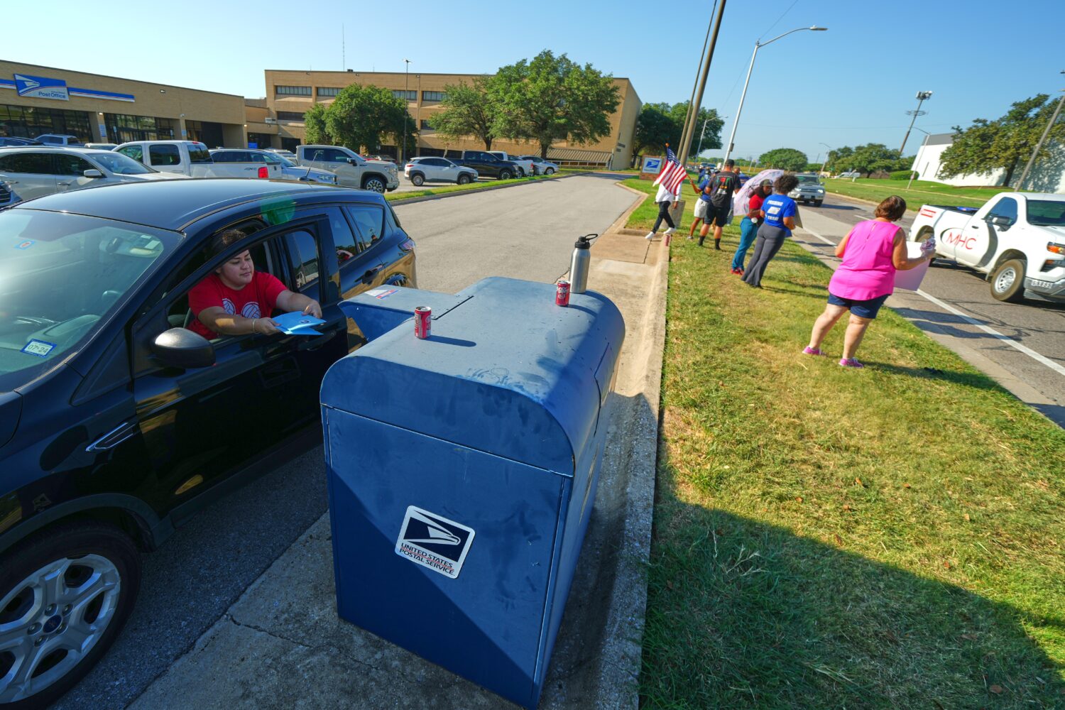 A person drops envelopes into a mailbox as postal workers participate in a national day of action o...