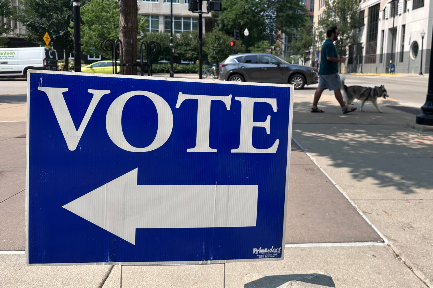 A person walks past a sign for a polling place on the first day of in-person absentee voting for Wi...