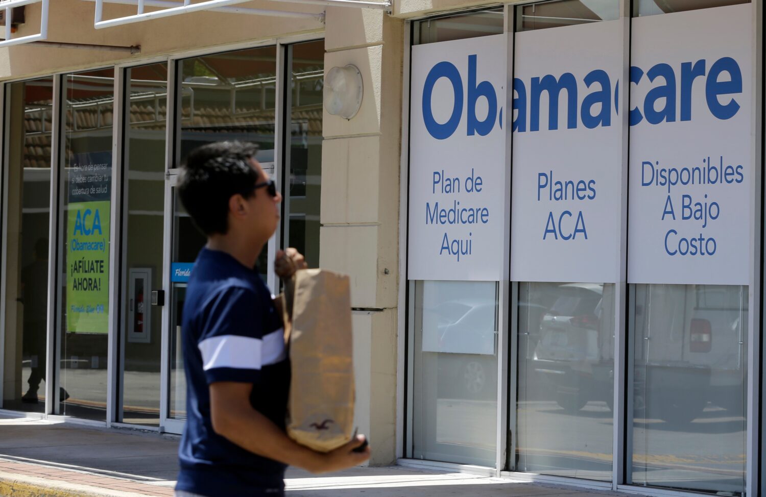 FILE - A man walks by an healthcare insurance office in Hialeah, Fla., July 27, 2017, (AP Photo/Ala...