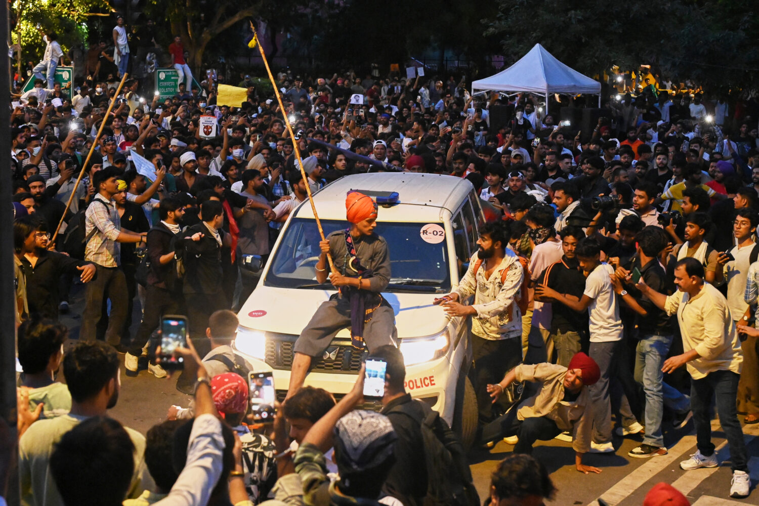 A protestor sits on the hood of a police car during a demonstration demanding educational reforms a...