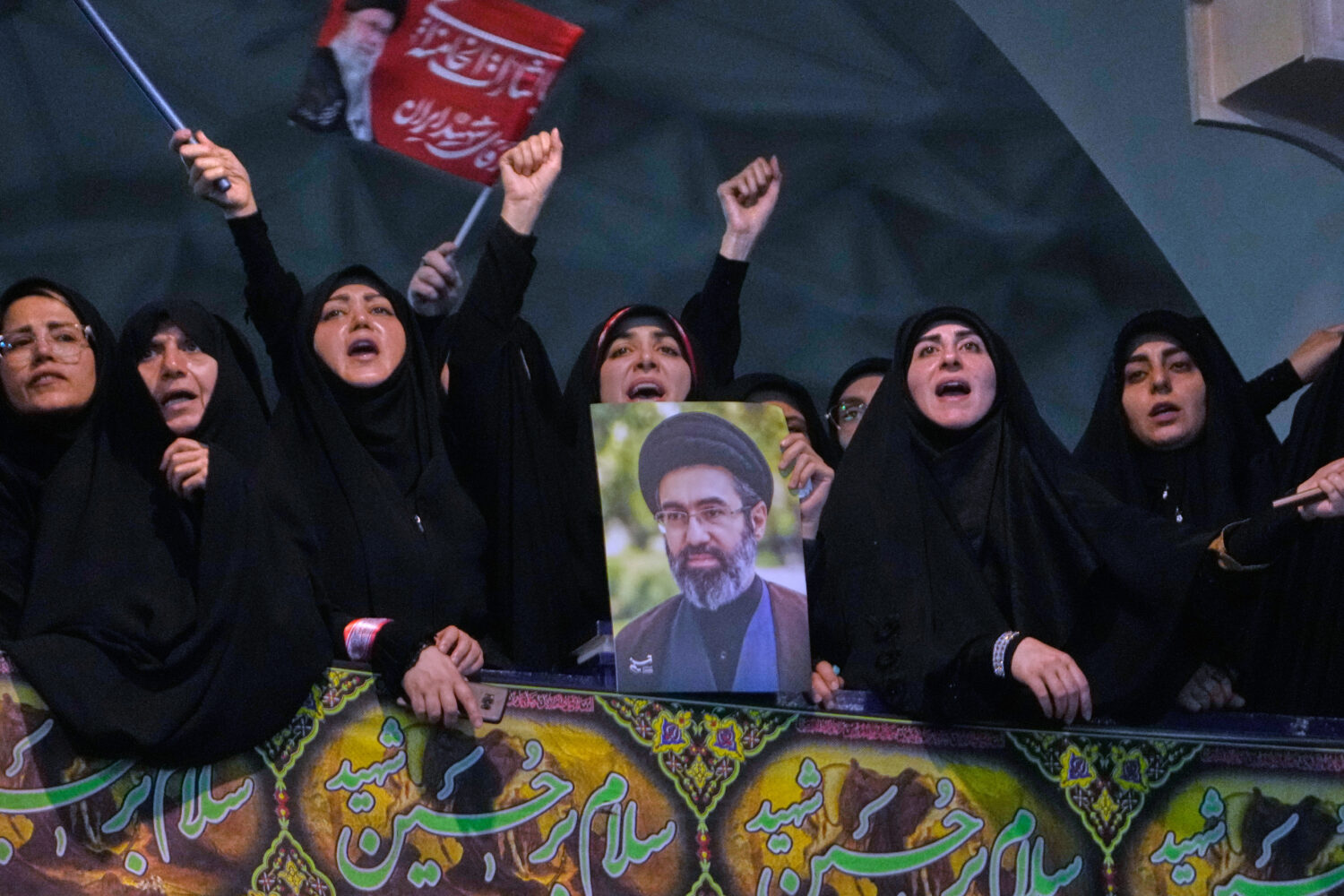 Mourners chant slogan as one of them holds a poster of the Supreme Leader Ayatollah Mojtaba Khamene...