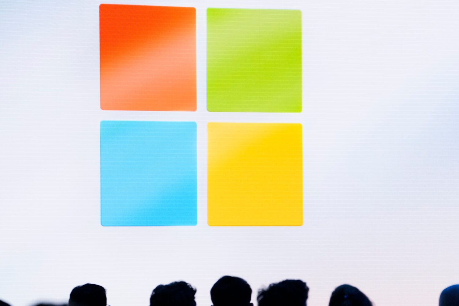 FILE - A Microsoft logo is seen on a screen as people listen at an event at Microsoft headquarters,...