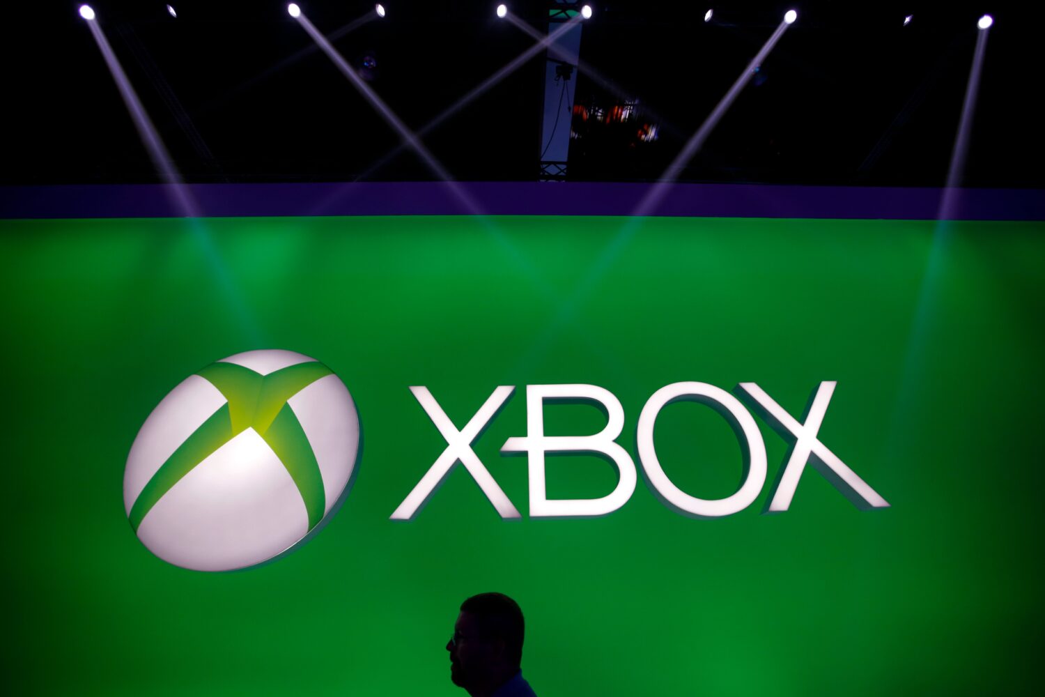FILE - A man walks past the Xbox logo at the Microsoft booth during the E3 game show in Los Angeles...