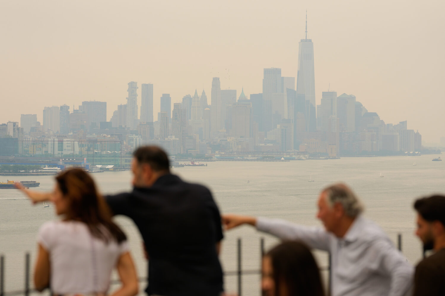 People look over the New York City skyline shrouded in smoke in Weehawken, N.J., Thursday, July 16,...