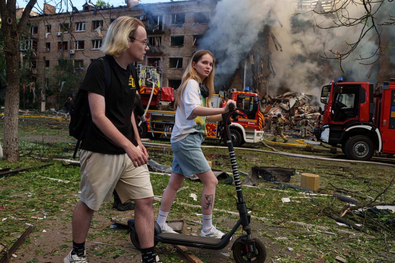 People walk past a smoldering residential building destroyed by a Russian strike in the Lukianivka ...