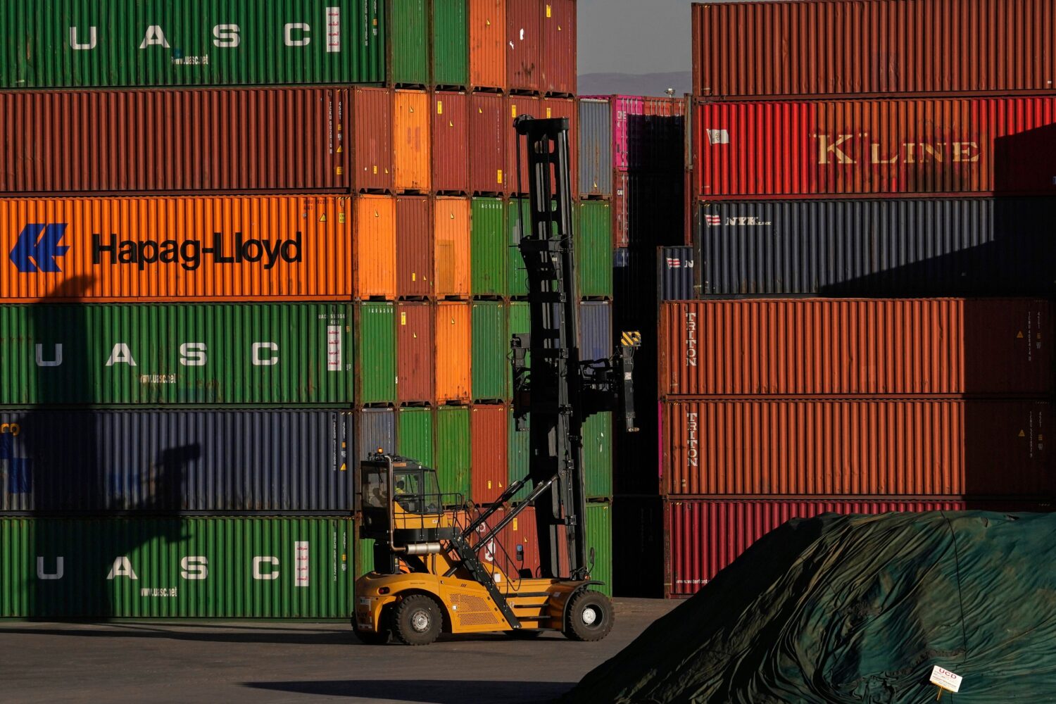 FILE - A heavy machine drives past shipping containers stacked at a depo, in Johannesburg, South Af...