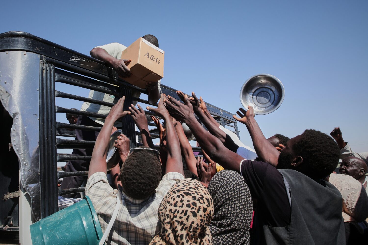 FILE.- Sudanese families displaced from El-Fasher reach out as aid workers distribute food supplies...