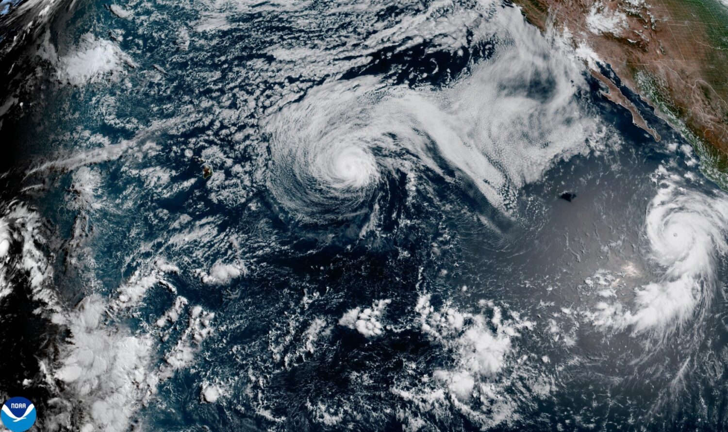 This satellite image released by NOAA shows Hurricane Fausto, center, and Hurricane Genevieve off t...