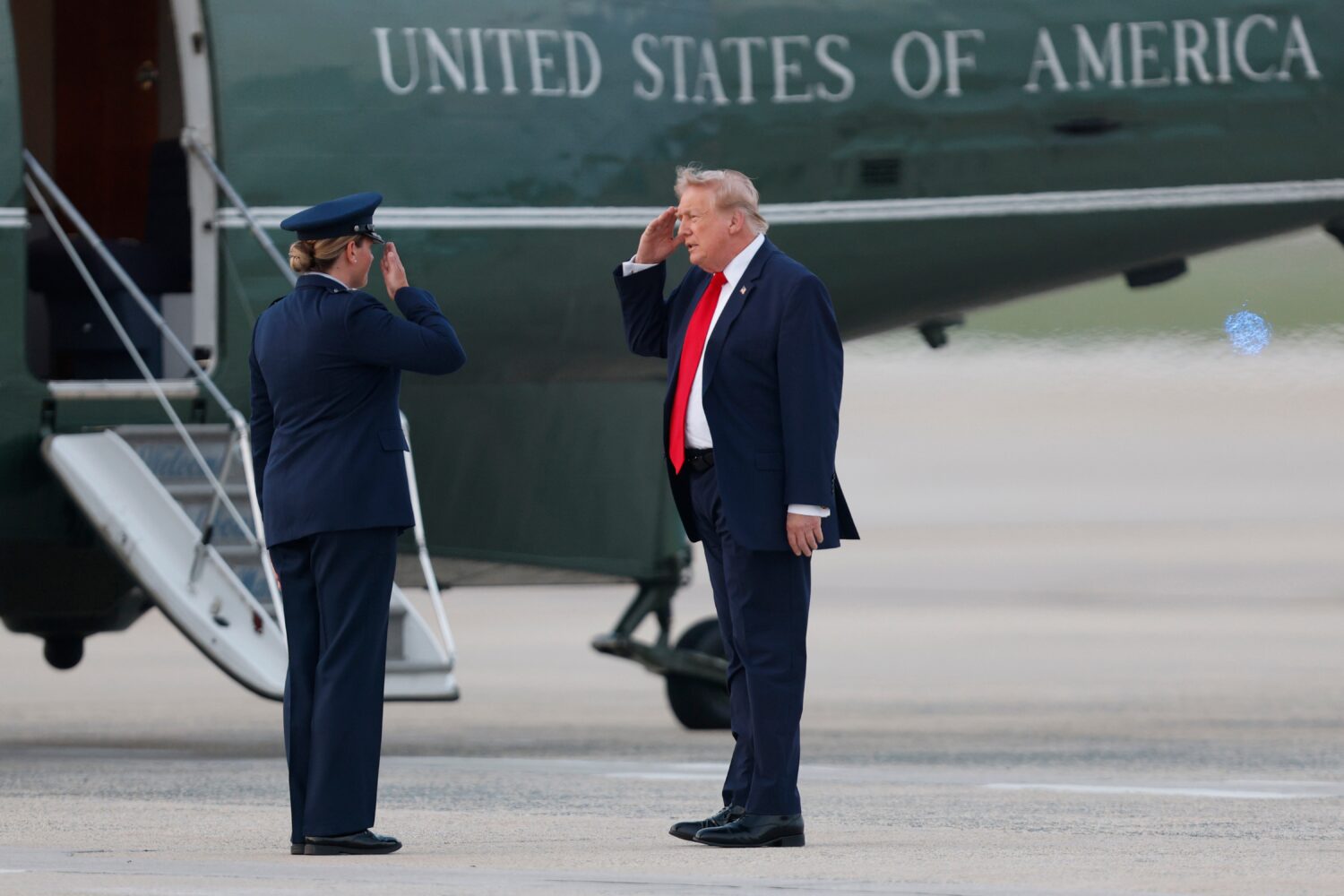 President Donald Trump, right, salutes Air Force 89th Air Wing Deputy Commander Melissa Dombrock, l...