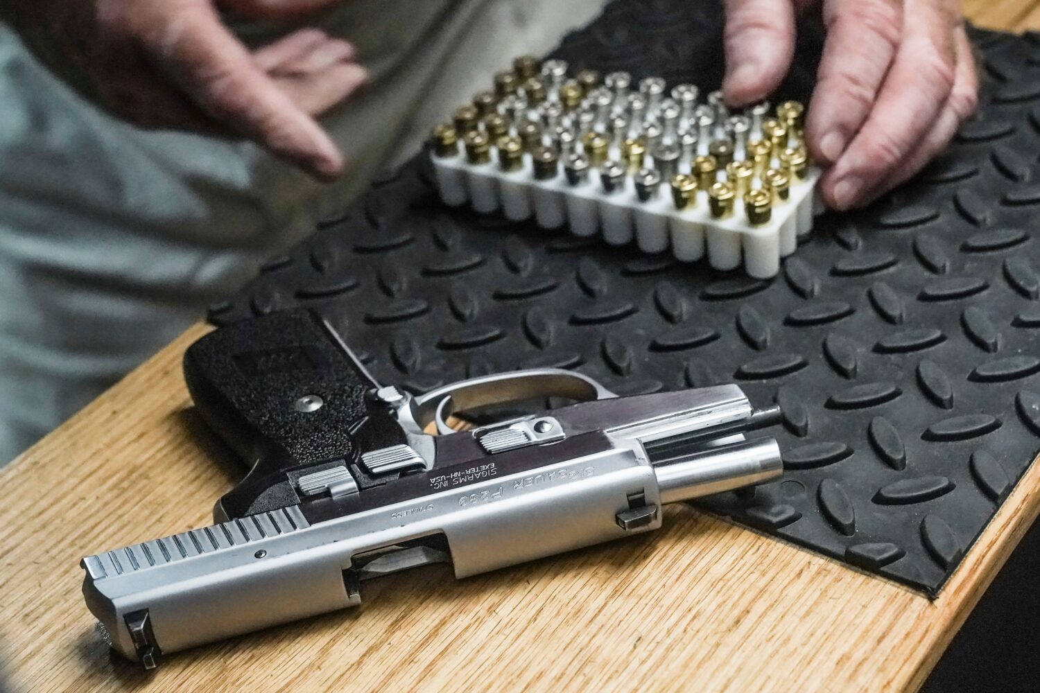 FILE - The owner of a shooting range prepares to load bullets in his 9mm semi-automatic handgun for...