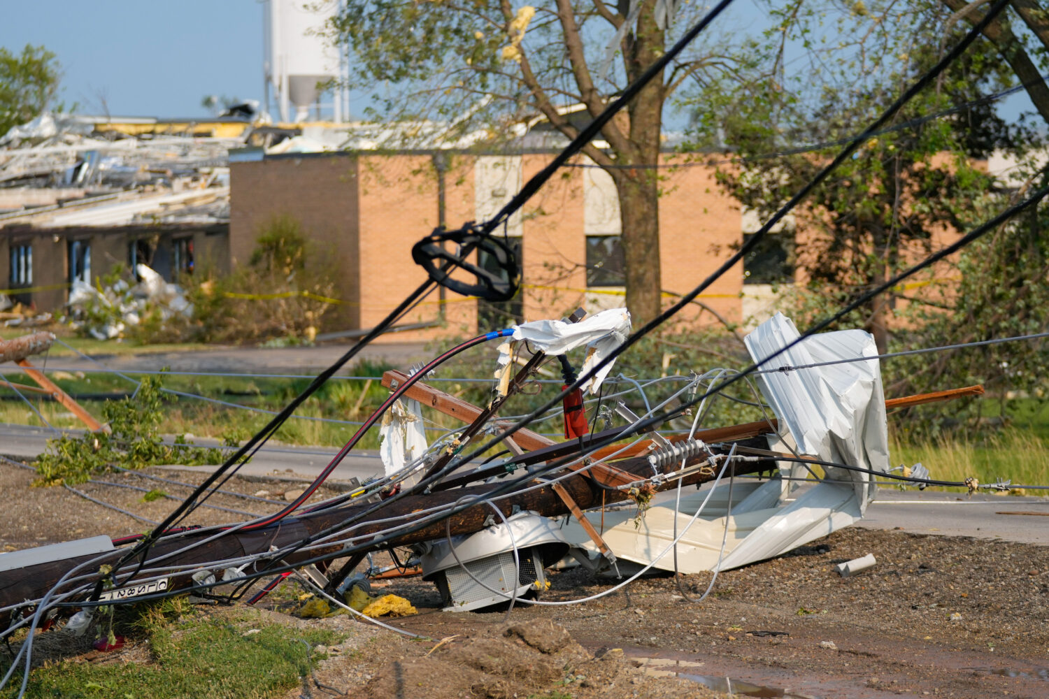 Power lines tangled with debris lie on the ground after a tornado tore through a day before in Appl...
