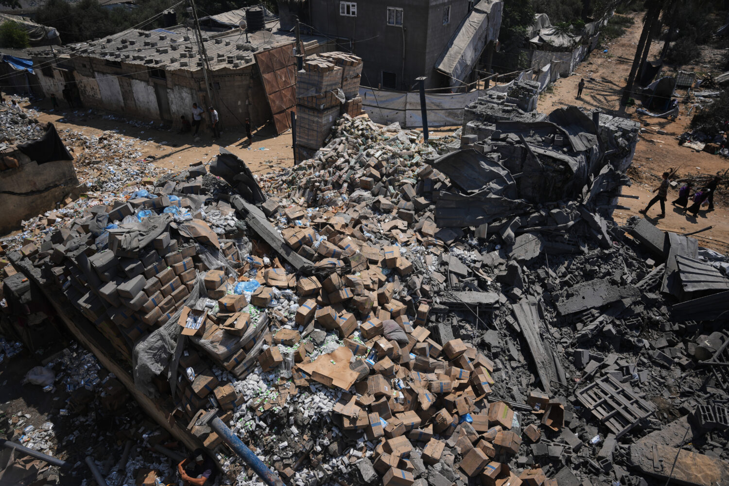 Palestinians walk past a food-aid warehouse damaged in an Israeli airstrike that targeted a nearby ...