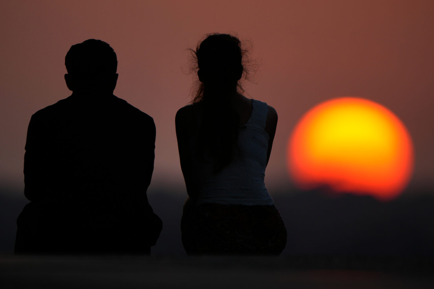 People watch the setting sun at the end of a hot summer day, Sunday, July 26, 2026, in Kansas City,...