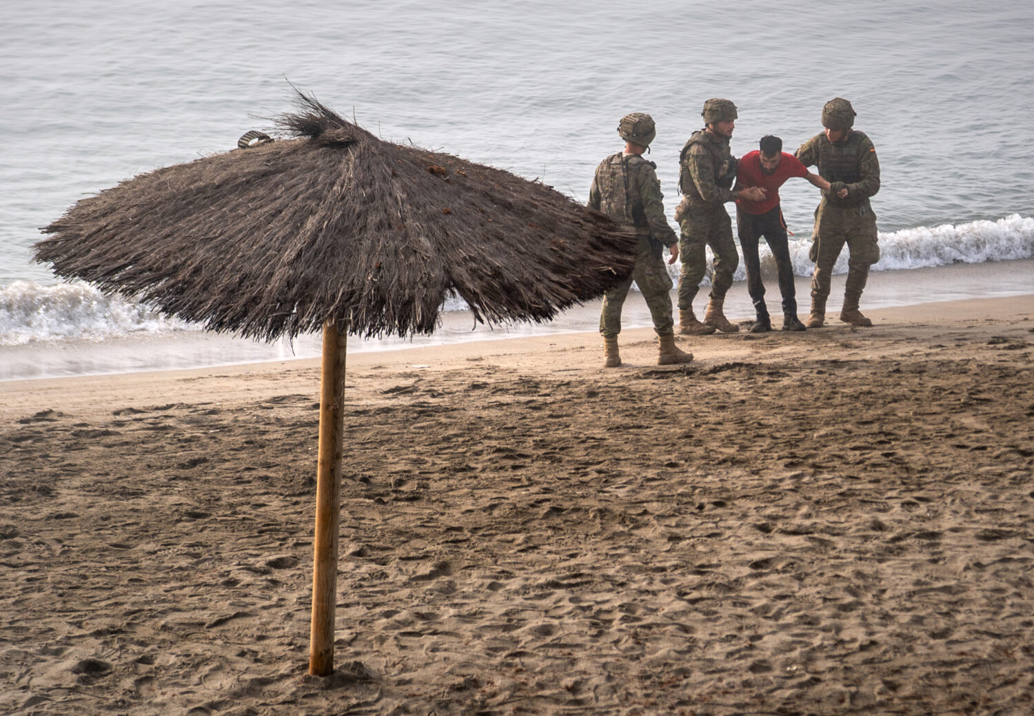 Spanish army soldiers assist a migrant who swam from Morocco to the Spanish enclave of Ceuta, Satur...