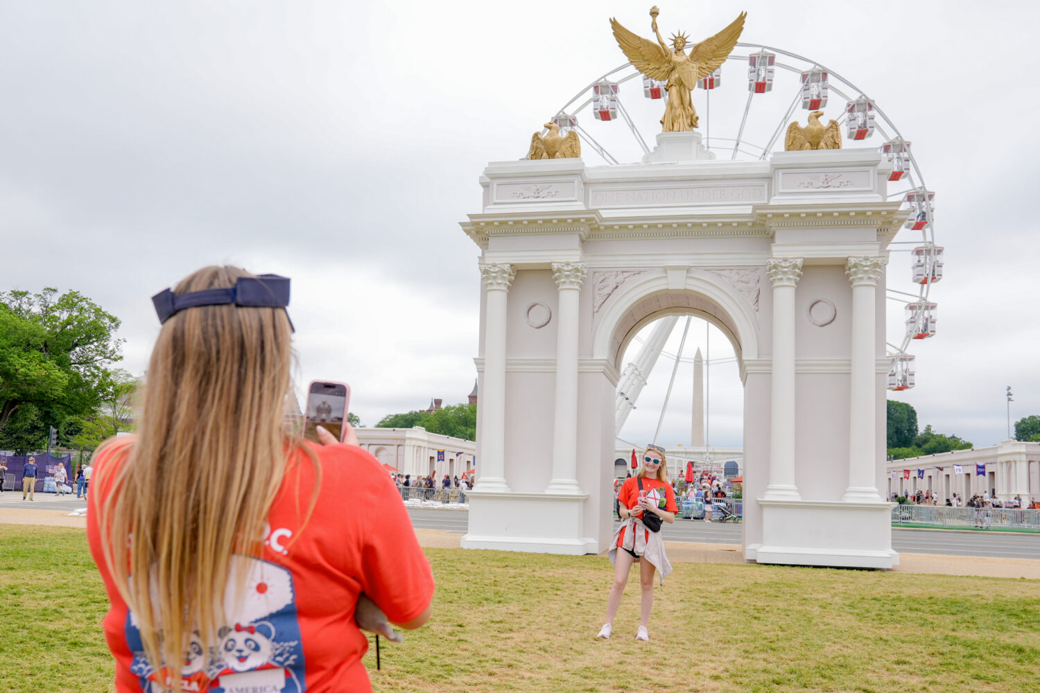 Visitors take photos at the Great American State Fair on the National Mall, with the ferris wheel a...