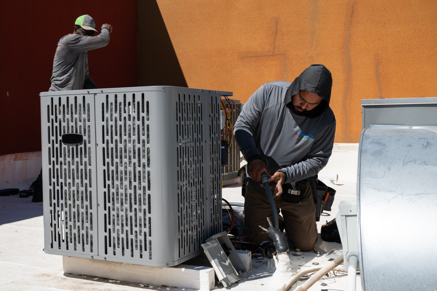 FILE - Sonel Telemaque, left, wipes sweat from his brow while installing a new air conditioning uni...