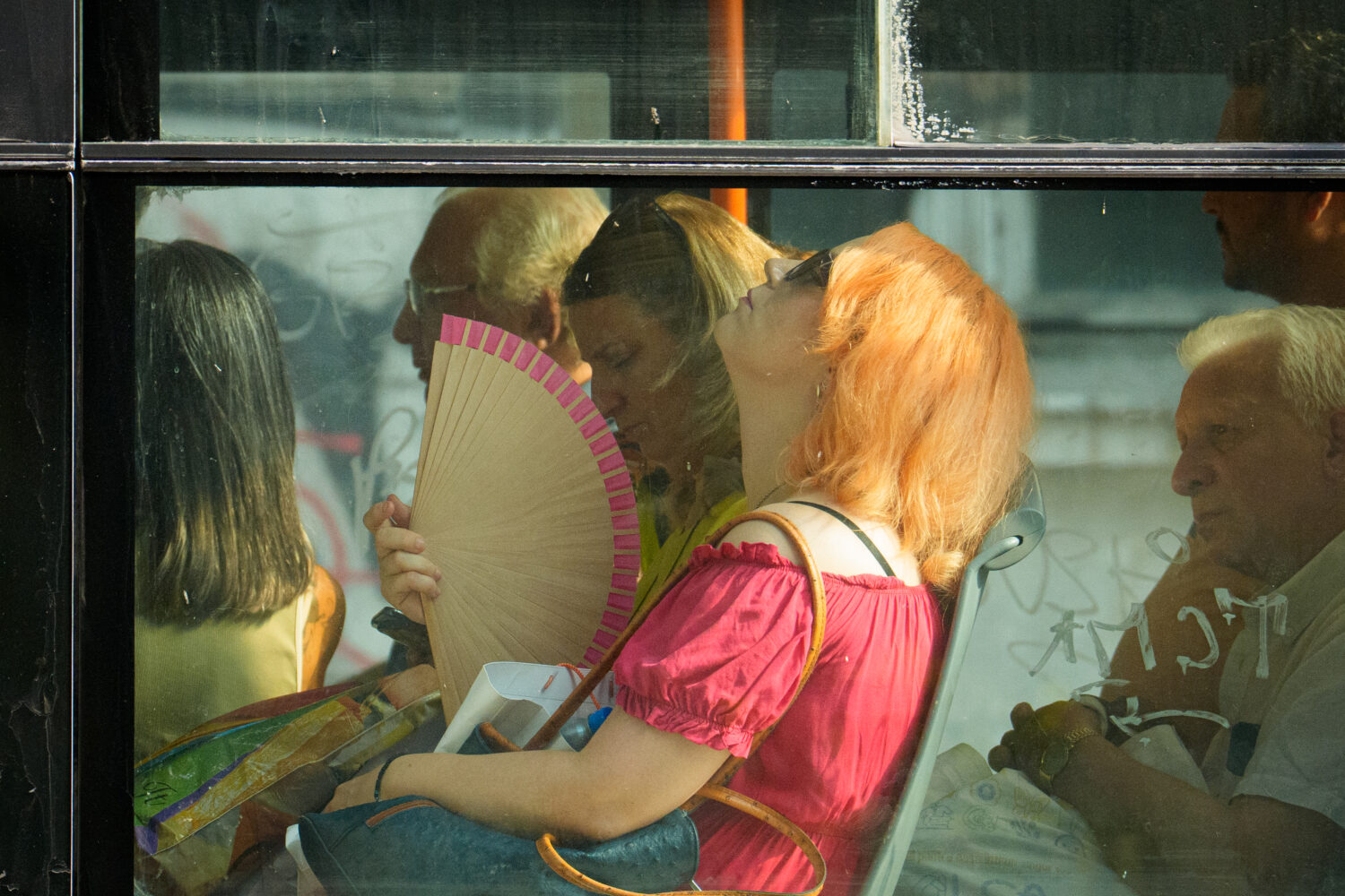 FILE - A woman uses a fan to cool off while riding a bus on a hot day in Bucharest, Romania, Aug. 6...