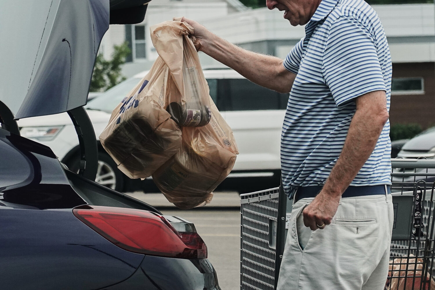 FILE - A person loads groceries in plastic bags into their vehicle, May 18, 2026, at a grocery stor...