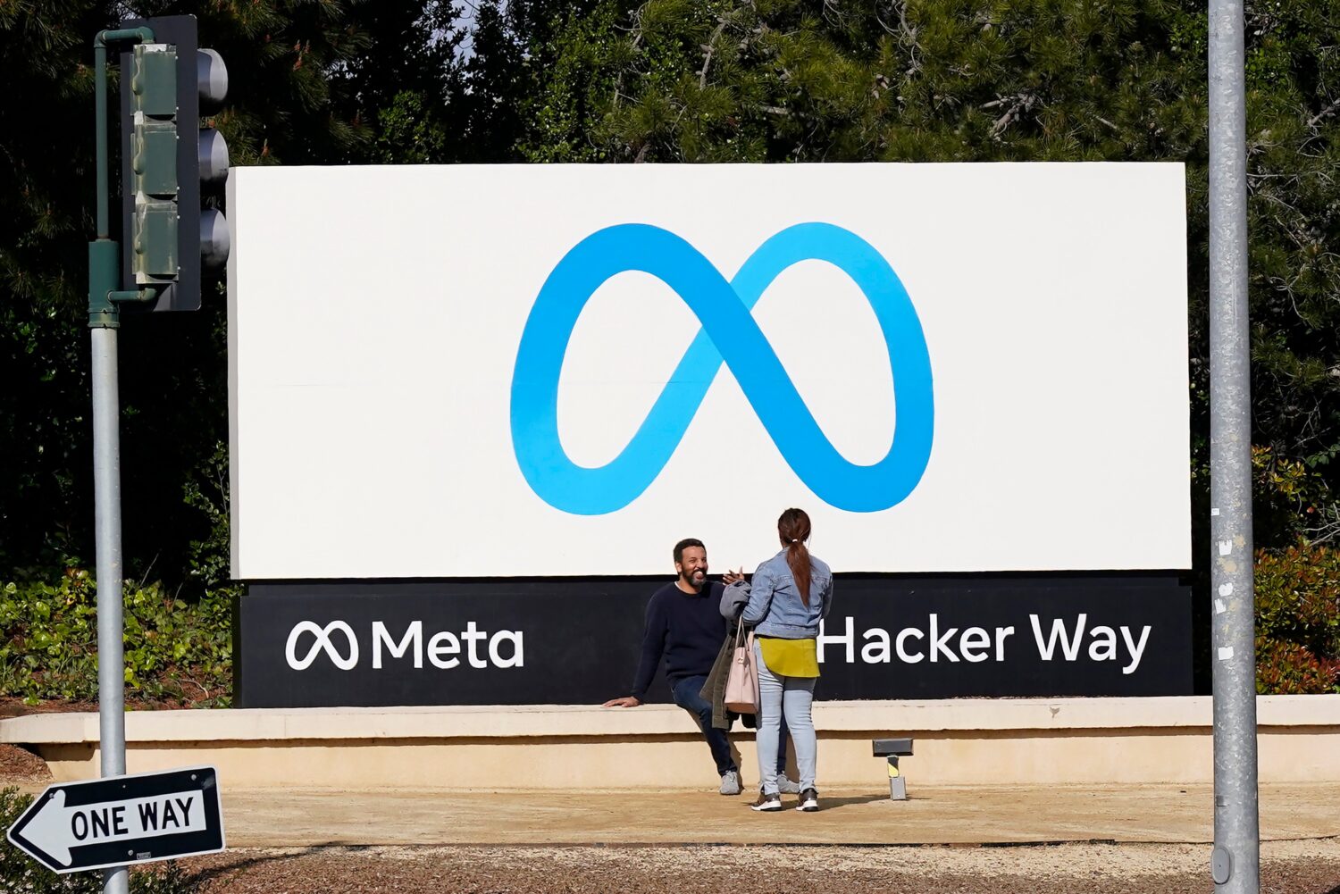 FILE - People talk near a Meta sign outside of the company's headquarters in Menlo Park, Calif., Ma...