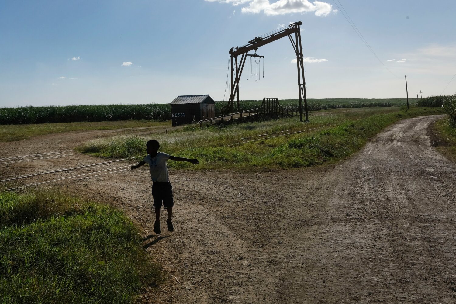 FILE - A youth plays near the machine where the sugar cane is weighed in the Lima batey, or neighbo...
