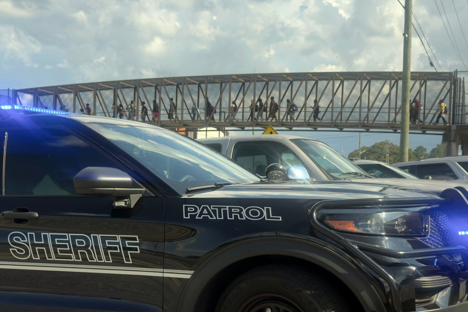 Students leave Warner Robins High School as Houston County Sheriff vehicles remain on the scene aft...