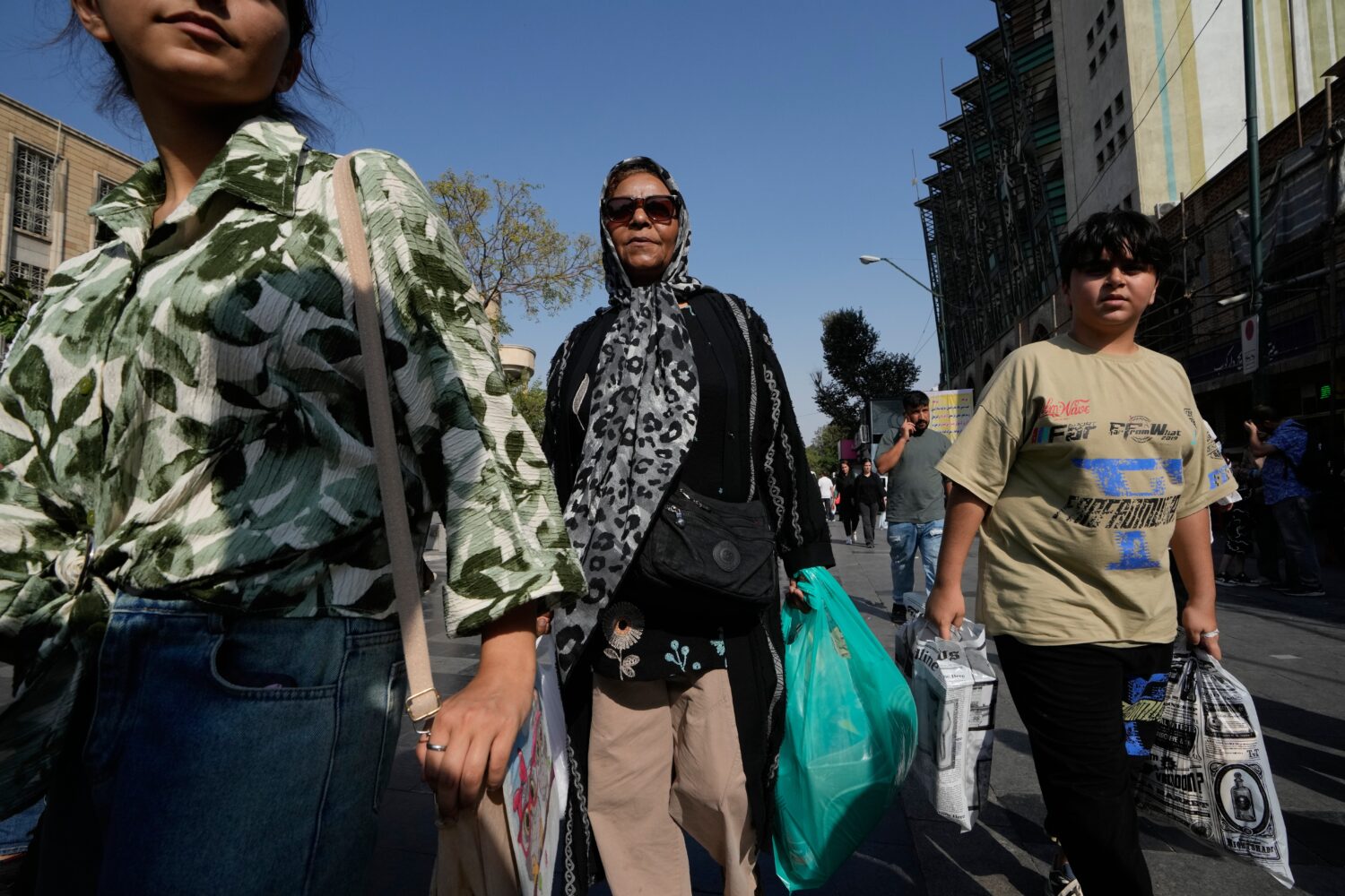 People carrying shopping bags walk through Tehran's Grand Bazaar in Tehran, Iran, Monday, Aug. 24, ...