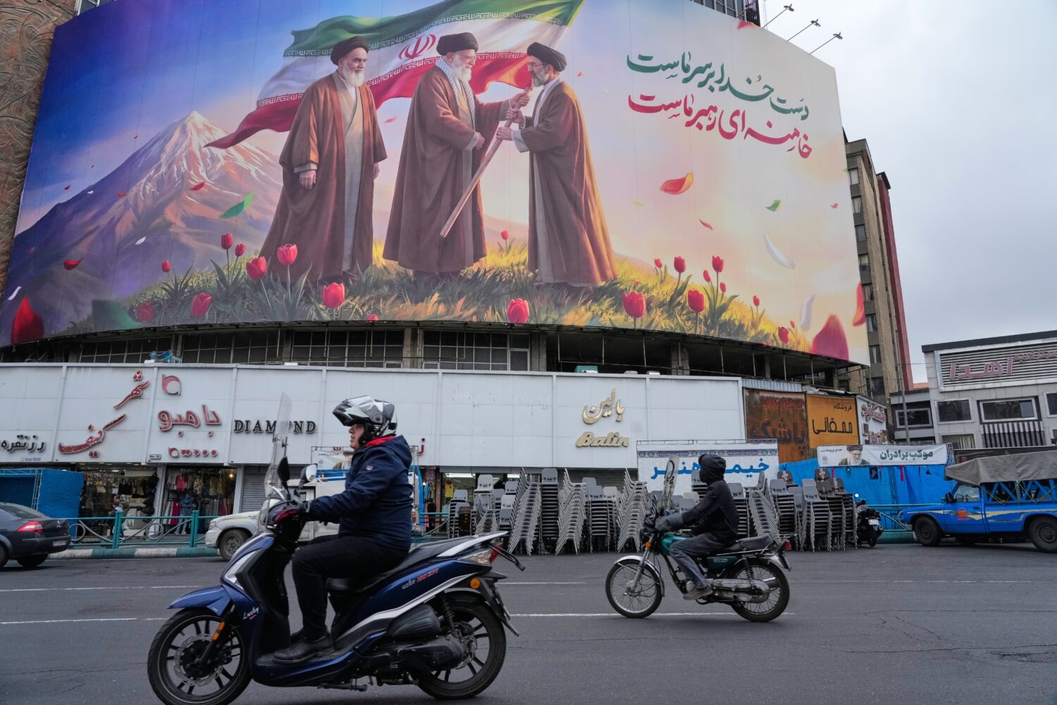 FILE - Motorbikes drive past a billboard depicting Iran's late Supreme Leader Ayatollah Ali Khamene...