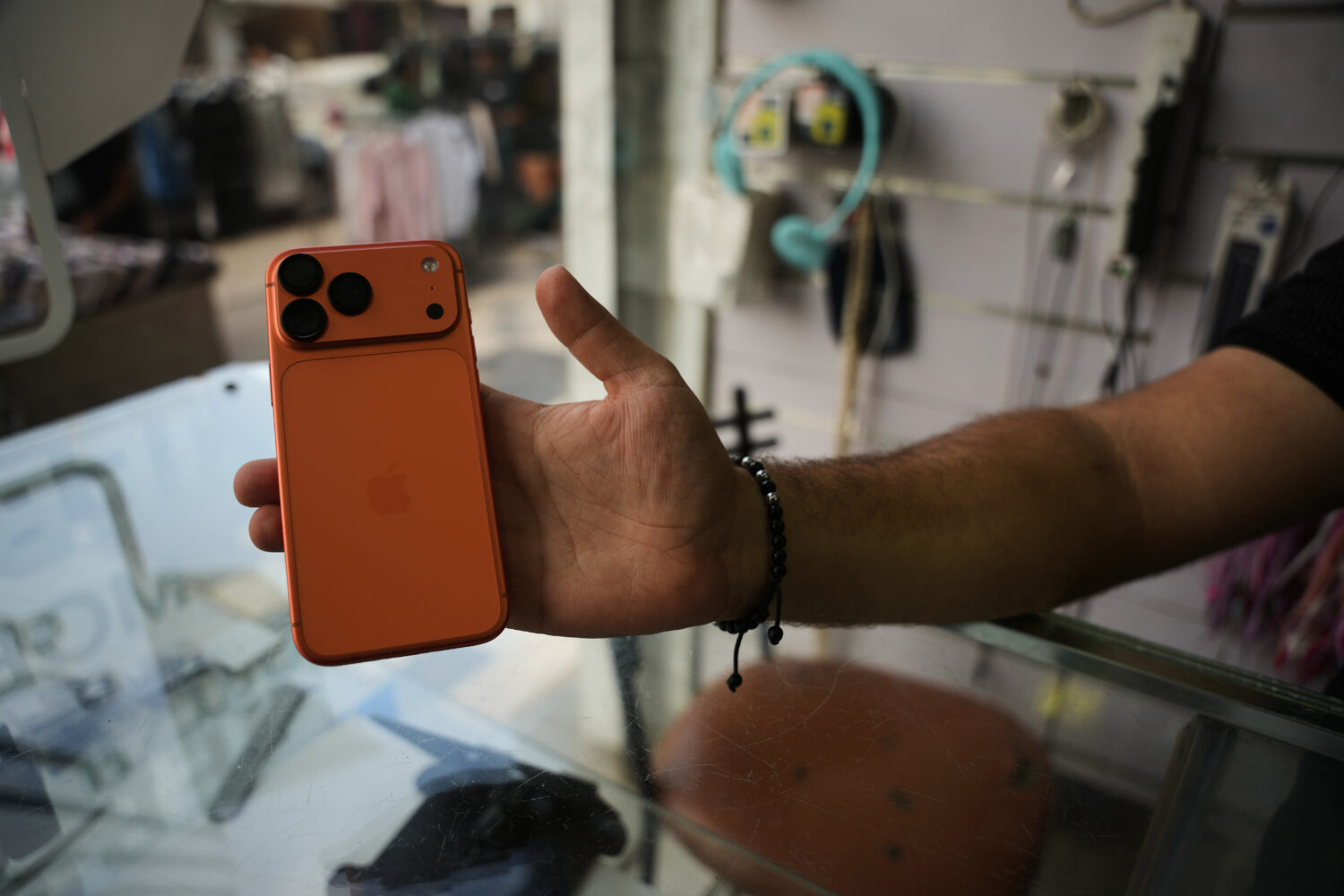 A Palestinian salesman shows an iPhone 17 Pro Max to the camera at a mobile phone store in Gaza Cit...