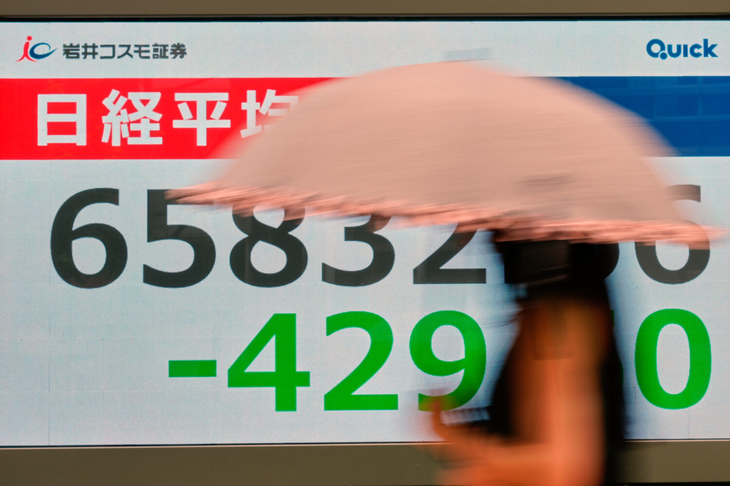 A person walks near an electronic stock board showing Japan's Nikkei index at a securities firm Thu...