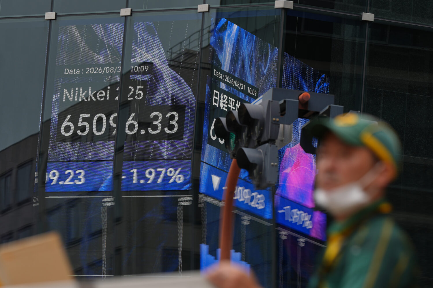 A person walks in front of an electronic stock board showing Japan's Nikkei index at a securities f...