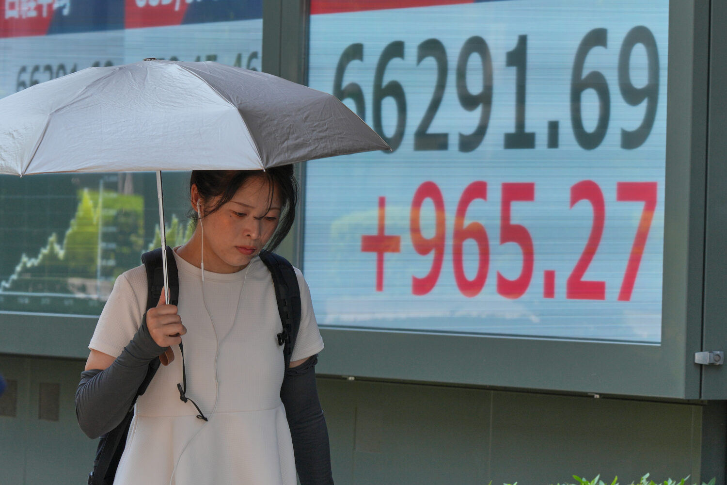 A person walks in front of an electronic stock board showing Japan's Nikkei index at a securities f...