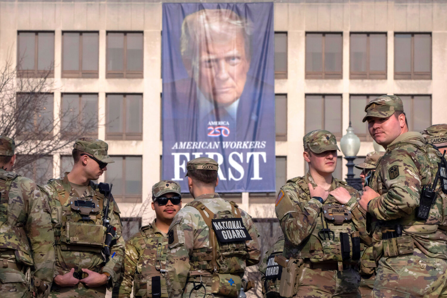 FILE - National Guard members gather near a large portrait of President Donald Trump on the Labor D...