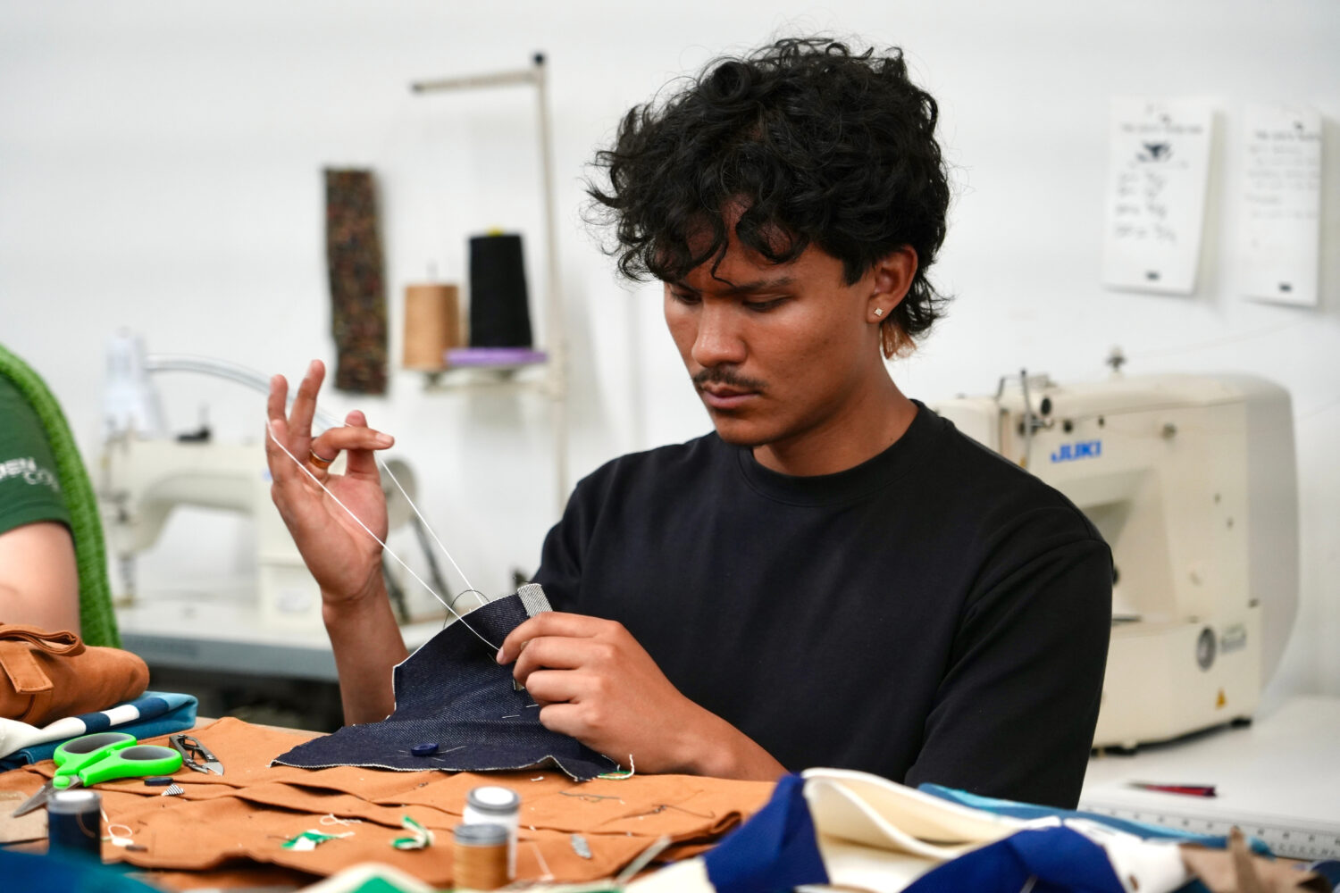 Jesse Sanchez practices sewing during a clothing repair workshop at a Levi's retail store in downto...