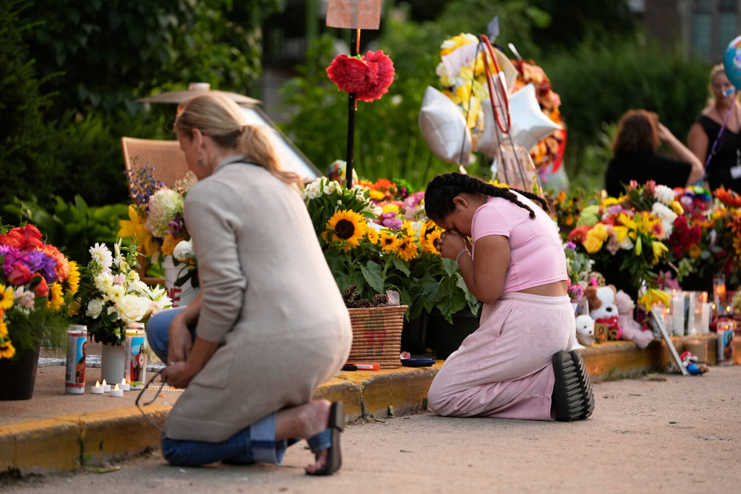 FILE - People pray at a memorial at Annunciation Catholic Church the day after a school shooting, A...