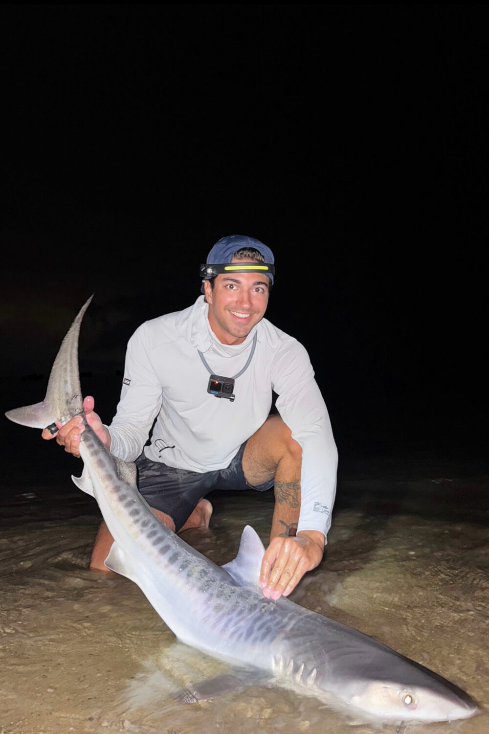 This photo provided by Nelson Rouette shows his brother, Nate Rouette, holding a young tiger shark ...