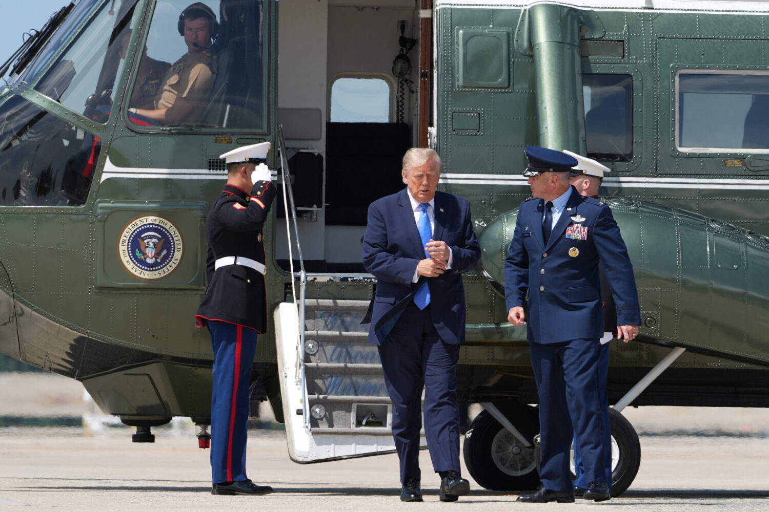 President Donald Trump walks from Marine One with Air Force Col. Christopher M. Robinson, commander...