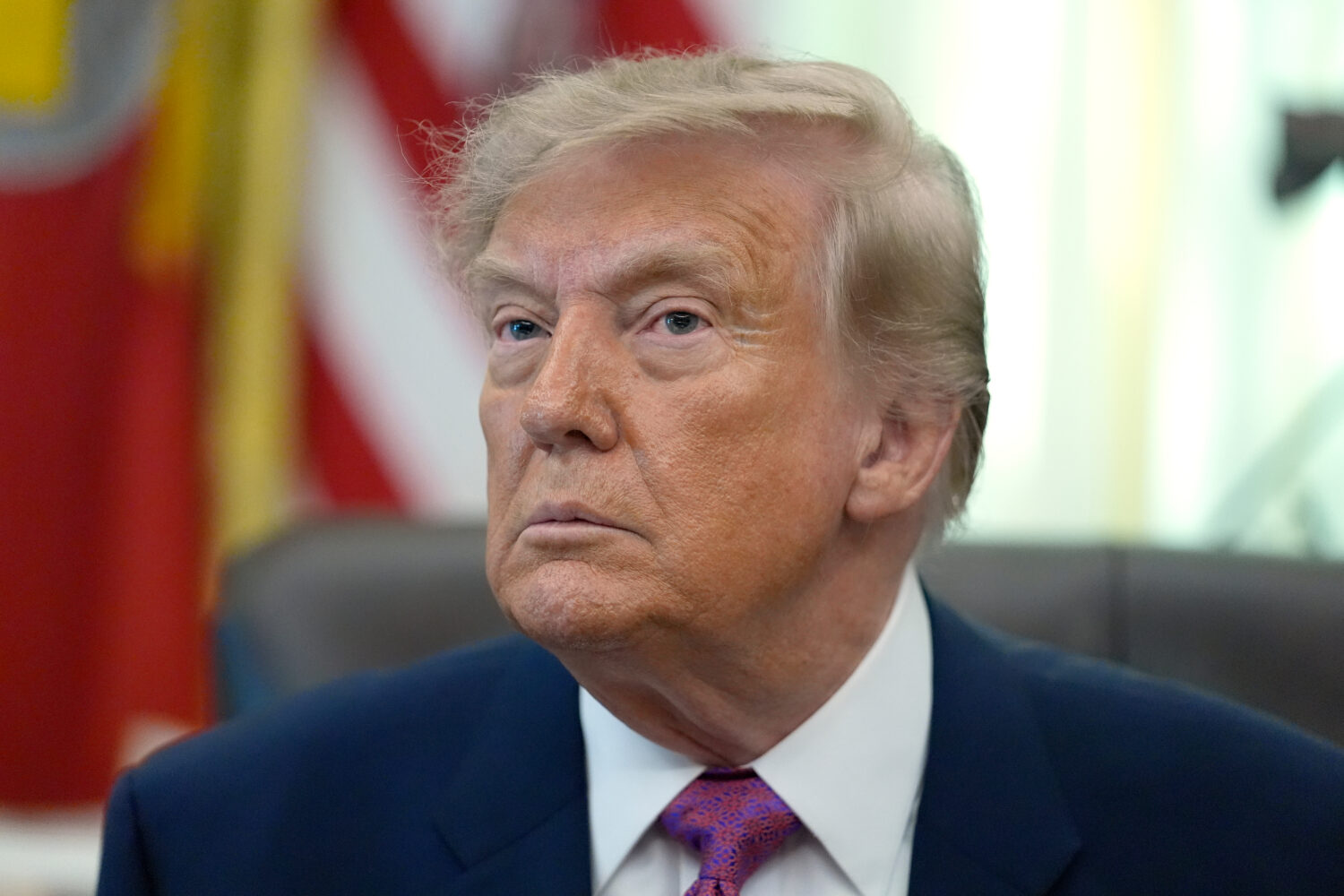 President Donald Trump listens to a question from a reporter in the Oval Office of the White House,...