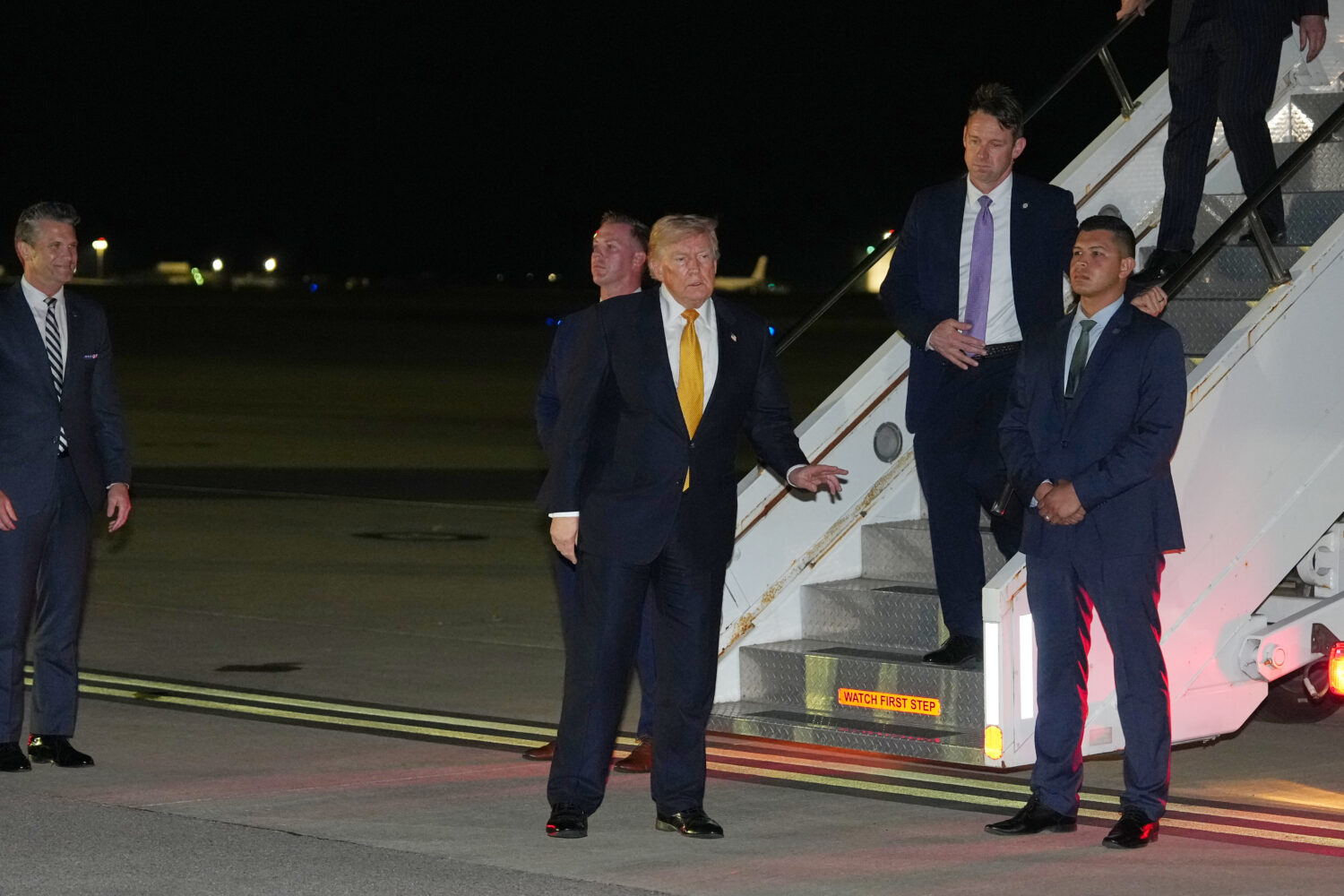 As Defense Secretary Pete Hegseth watches at left, President Donald Trump gestures as he switches p...