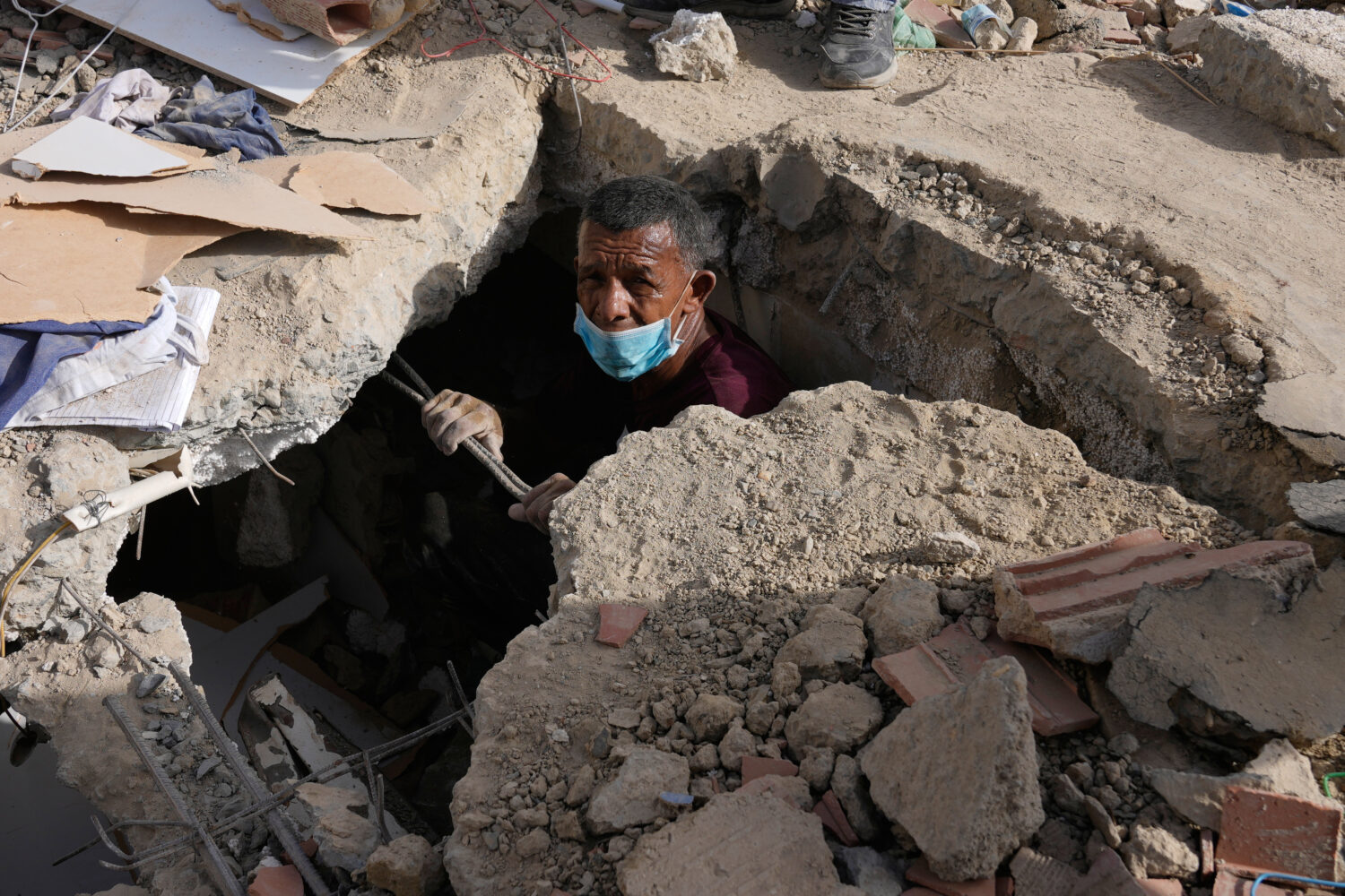 FILE - Franklin Fuentes searches for missing relatives in the collapsed building where they lived t...