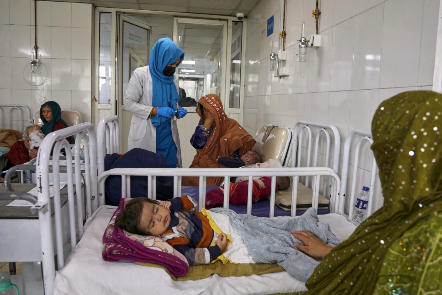 FILE - Afghan women care for their children in the malnutrition ward at Indira Gandhi Children's Ho...