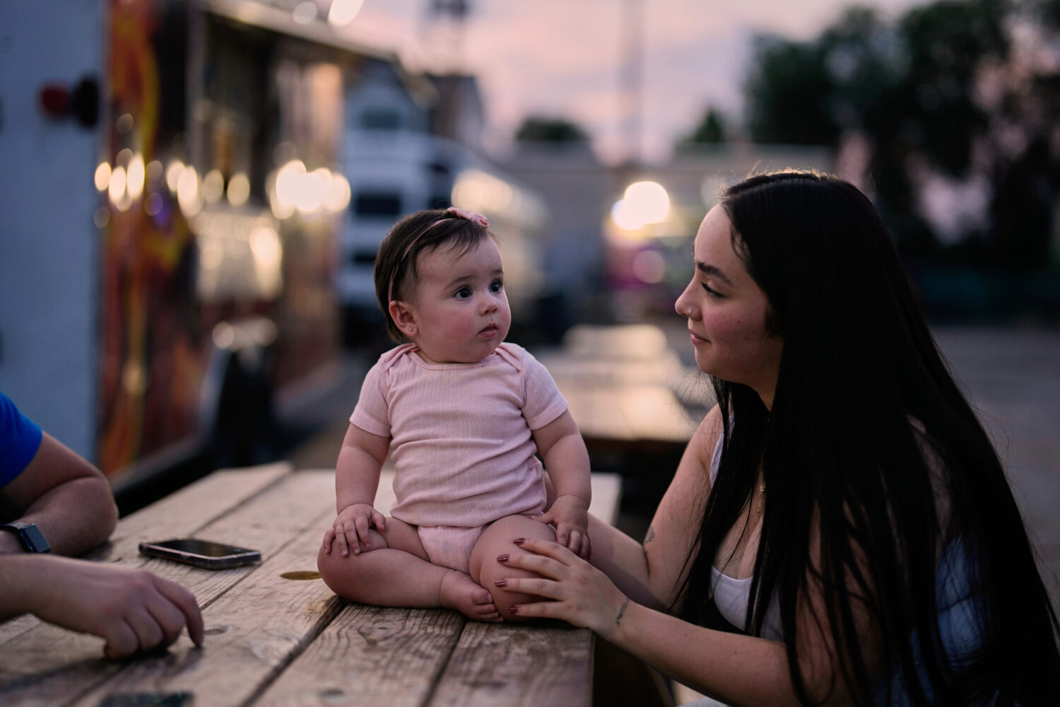 A Venezuelan mother sits with her daughter among food trucks Tuesday, July 14, 2026, in Midvale, Ut...